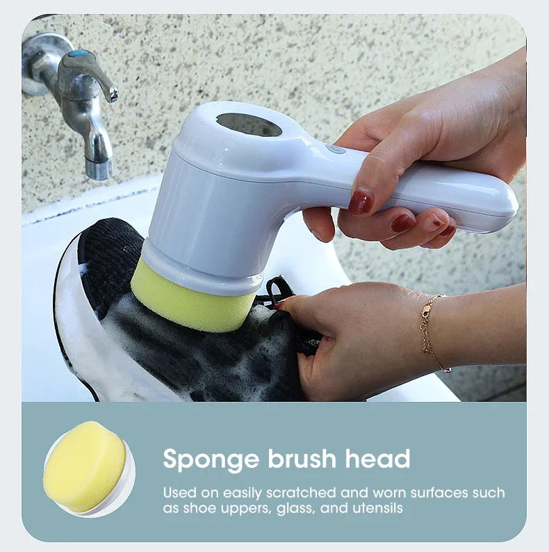 Hand holding a white handheld scrubber with a yellow sponge head over a sink.
